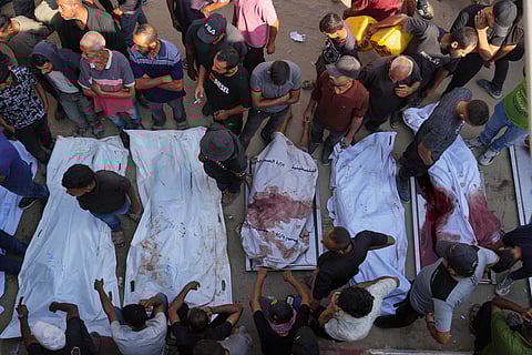 Palestinians mourn over the bodies of people killed either by Israeli military strikes or while trying to reach aid trucks, outside Shifa Hospital, in Gaza City, Thursday, Aug. 21, 2025.