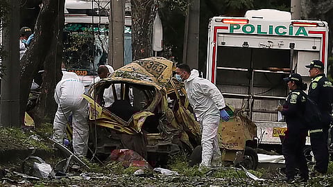 Security forces inspect the site of a bomb explosion outside an Air Force base in Cali, Colombia, Thursday, Aug. 21, 2025.
