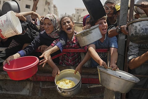 Palestinians struggle to get donated food at a community kitchen in Gaza City, northern Gaza Strip, Saturday, August 16, 2025.