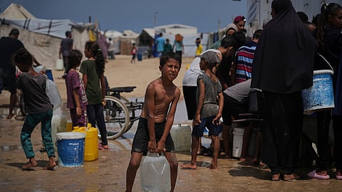 Displaced Palestinians gather to collect water from a truck during a heat wave at a makeshift tent camp in Khan Younis, Gaza Strip, Wednesday, Aug. 13, 2025.