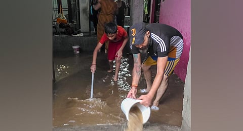 Locals remove rainwater inundating their house after heavy rainfall, at Kabir Colony, in Jammu, Sunday, Aug. 24, 2025.