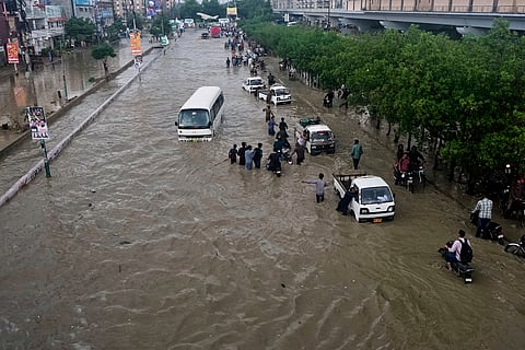 Drivers push their vehicles through a flooded road after heavy rainfall in Karachi, Pakistan, Tuesday, Aug. 19, 2025.