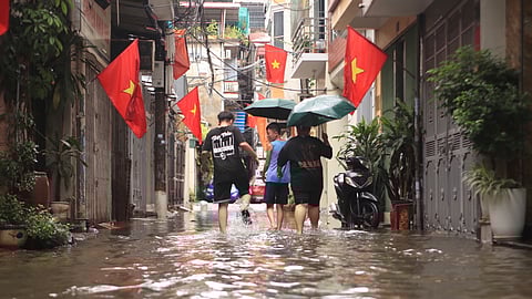 People wade through a flooded alley caused by Typhoon Kajiki in Hanoi, Vietnam, Tuesday, Aug. 26, 2025.