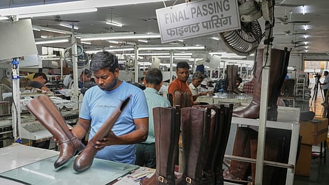 A worker inspects high ankle leather boots before packing in a leather footwear manufacturing unit at Dawar industry in Agra, India, Monday, Aug. 25, 2025.