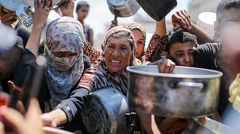 People try to get rice from a charity kitchen providing food for free in the west of Gaza City, on August 28, 2025.
