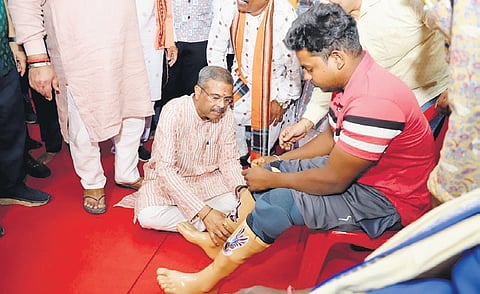 Union Minister Dharmendra Pradhan helps in fixing artificial limbs on a patient