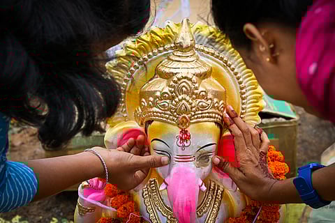 Women erase the eye of Ganesha Idol before immersing it at the temporary pond at Kuakhai river in Bhubaneswar on Friday.