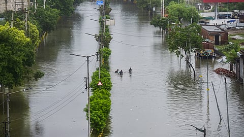 People make their way through a submerged area after heavy rainfall in Punjab.