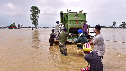 Security personnel and locals pull a boat loaded with an agricultural machine, through a flooded area, in Kapurthala, Punjab, Wednesday, Sept. 3, 2025.