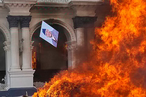 A protester throws a photograph of Nepal Prime Minister Khadga Prasad Oli in the fire at the Singha Durbar, the seat of Nepal's government's various ministries and offices during a protest against social media ban and corruption in Kathmandu, Nepal, Tuesday, Sept. 9, 2025.