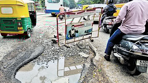 Motorists take extra care to navigate around a deep pothole at a signal near the BMTC bus station in Shantinagar on Tuesday.