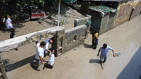 People walk in the mud remains after Yamuna water receded, at Yamuna Bazar in New Delhi on Monday.