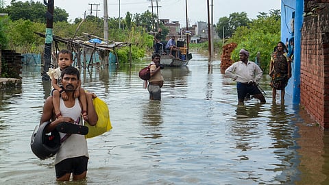 Locals carry their belongings as they wade through floodwater of the swollen Ganga river inundating a village, in Kanpur district, Uttar Pradesh, Tuesday, Sept. 9, 2025.