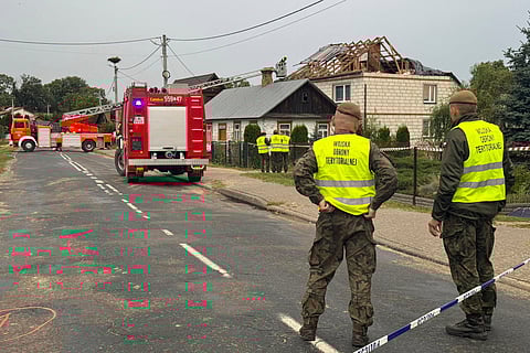 Firefighters and territorial defence officers stand close to the destroyed roof of a house, after Russian drones violated Polish airspace during an attack on Ukraine, in Wyryki near Lublin, Poland, Thursday, Sept. 11, 2025.