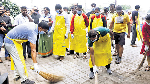 Bengaluru Central City Commissioner Rajendra Cholan (left) and other GBA staff clean a footpath in Majestic