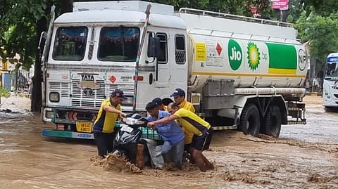 Vehicles and people wade through flooded roads in Uttarkhand.