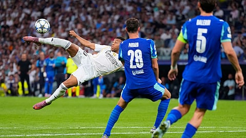 Real Madrid's Kylian Mbappe, left, shoots a high ball next to Marseille defenders during a Champions League opening phase soccer match between Real Madrid and Marseille at Santiago Bernabeu stadium, in Madrid, Tuesday, Sept. 16, 2025.