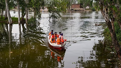 Officials inspect a flood-affected area in a boat, at Ajnala in Amritsar district, Punjab