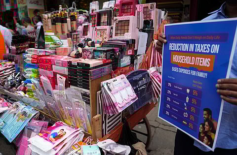 A vendor holds a poster to celebrate the GST reforms in Bengaluru (Photo | PTI)