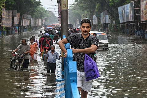 Commuters make their way through a waterlogged road following rain, in Kolkata, Tuesday, Sept. 23, 2025.