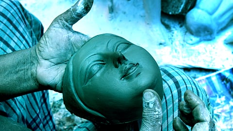Artist Tapan Jena prepares the face of Goddess Durga's idol inside a shed in Kadavanthra, with clay collected from the banks of the Hooghly river in West Bengal