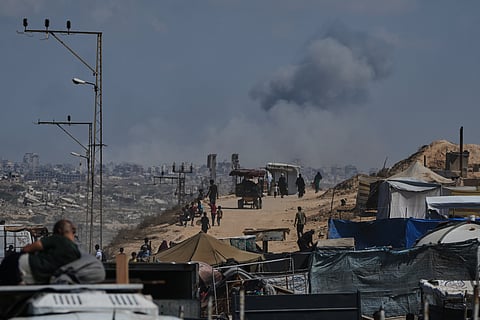 Smoke billows over Gaza City following an Israeli airstrike, as displaced Palestinians flee northern Gaza through Wadi Gaza, Wednesday, Sept. 24, 2025.