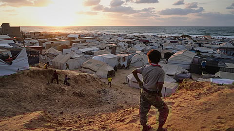 Displaced Palestinians walk through a tent camp in Muwasi, an area that Israel has designated as a safe zone, in Khan Younis southern Gaza Strip, Thursday, Sept. 25, 2025.