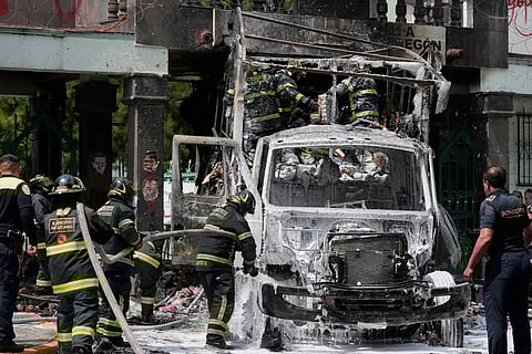 Firefighters extinguish a garbage truck that demonstrators set on fire during a protest marking the 11th anniversary of the disappearance of 43 students from an Ayotzinapa rural teacher's college, outside the entrance of Campo Militar, in Mexico City, Thursday, Sept 25, 2025.
