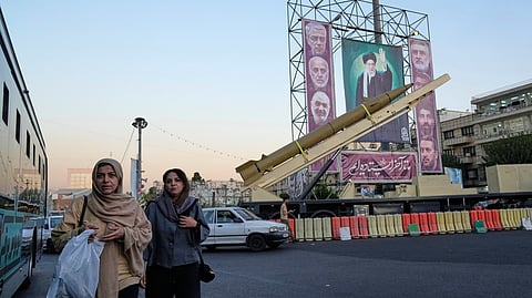 People walk past a domestically-built missile "Khaibar-buster," and banners showing portraits of the Iranian Supreme Leader Ayatollah Ali Khamenei, center, and the late armed forces commanders, who were killed in Israeli strike in June, displayed in a military exhibition commemorating the anniversary of the start of the 1980-88 Iraq-Iran war, and 12-day war with Israel in June, at Baharestan Square in Tehran, Thursday, Sept. 25, 2025.