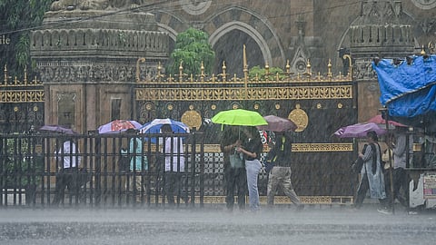 People open umbrellas amid the rain near Chhatrapati Shivaji Maharaj Terminus, in Mumbai.