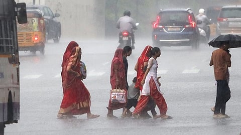 Women crossing the road as rain lashes.