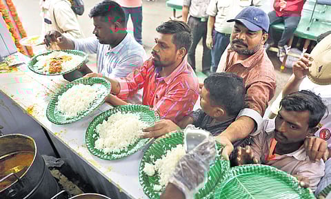 Workers serve rice and sambar to people during lunchtime at an Indiramma Canteen at Mint Compound, in Hyderabad on Monday