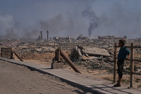 A displaced Palestinian boy looks at smoke rising into the sky following an Israeli military strike in Gaza City, as seen from the central Gaza Strip, Thursday, Oct. 2, 2025.