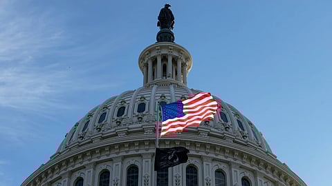 The American flag over the Capitol is illuminated by the early morning light on the first day of a government shutdown, in Washington, Wednesday, Oct. 1, 2025.