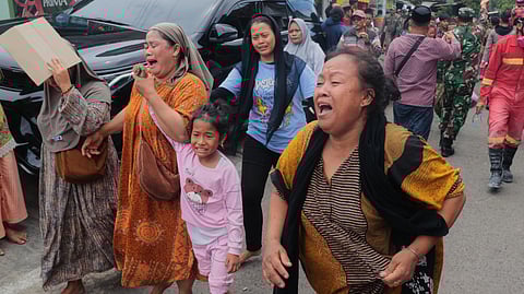 Women react as they move away after a building collapsed at an Islamic boarding school in Sidoarjo, East Java, Indonesia, Tuesday, Sept. 30, 2025.