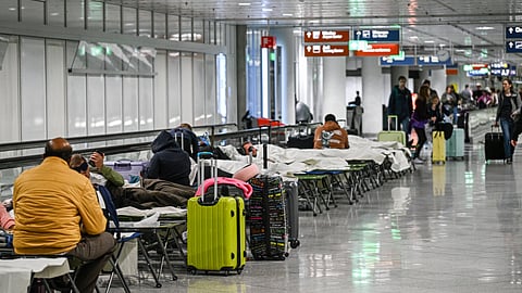 People wait on cots after drone sightings and flight cancellations at at Munich Airport, Friday, Oct.3, 2025.
