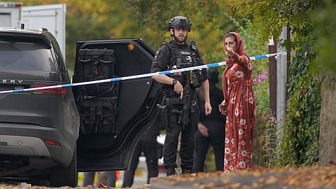 An armed police officer speaks to member of the public near the scene of a stabbing incident at Heaton Park Hebrew Congregation synagogue, in Crumpsall, Manchester, England, Thursday, Oct. 2, 2025.