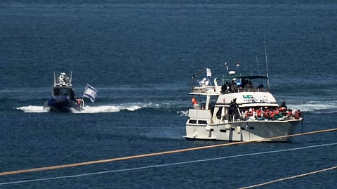 Activists in orange life jackets sit aboard a Gaza-bound Sumud flotilla boat as Israeli navy soldiers sail it into the port of Ashdod, Israel, Thursday, Oct. 2, 2025, after it was intercepted while approaching the Gaza coast.