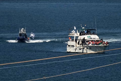 Activists in orange life jackets sit aboard a Gaza-bound Sumud flotilla boat as Israeli navy soldiers sail it into the port of Ashdod, Israel, Thursday, Oct. 2, 2025, after it was intercepted while approaching the Gaza coast.