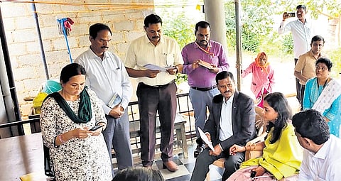 Member of the Karnataka State Commission for Backward Classes GN Srikantaiah (seated) and other officials at a caste survey site in Tumakuru district.