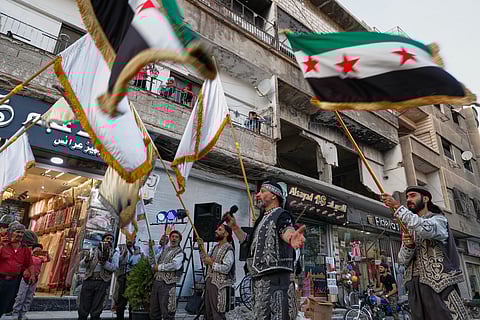 Residents watch a celebration below marking the opening of a new shop in the Damascus suburb of Daraya, Syria, Saturday, Oct. 4, 2025, ahead of a parliamentary election set to take place Sunday.