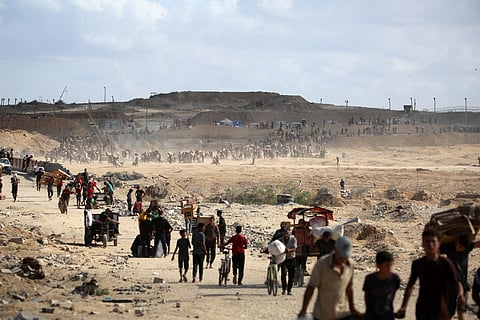 Palestinians carry bags and empty cardboard boxes as they leave a food distribution point run by the US and Israeli-backed Gaza Humanitarian Foundation (GHF) group, near the Netsarim corridor in the central Gaza Strip on October 5, 2025.