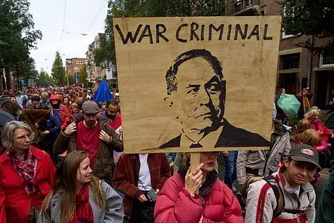 A woman carries a placard with a picture of Israeli Prime Minister Benjamin Netanyahu as tens of thousands of protesters march demanding their government do more to halt Israel's campaign in Gaza, during a demonstration in Amsterdam, Netherlands, Sunday, Oct. 5, 2025.