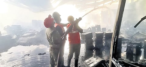 Fire fighters trying to put out the flames after a fire broke out in an electronics goods storage warehouse at Enikepadu near Vijayawada on Sunday night