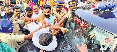 Cops removing a protester who stopped a forest department vehicle at Adimali town