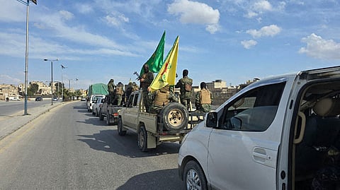 Vehicles carrying Kurdish fighters driving on a road as they leave two neighbourhoods in Syria's northern city of Aleppo.