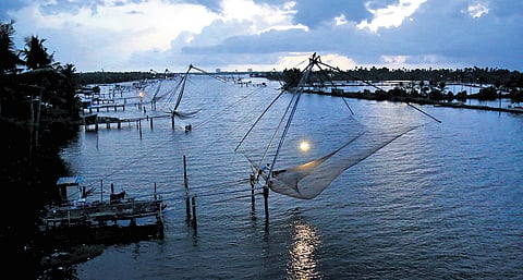 A man lowers a Chinese fishing net into the water off Pizhala