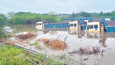 Trucks laden with iron ore inundated in flood waters at Challakere taluk of Chitradurga district on Thursday.