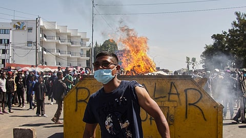 An protester watches police near burning barricades during a protest calling for the president to step down in Antananarivo, Madagascar, Thursday, Oct. 9, 2025.