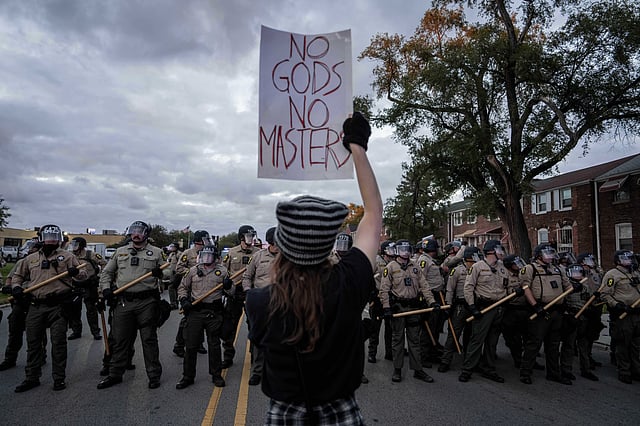 A demonstrator holds a sign as Illinois State Police move the crowd back after declaring an unlawful assembly outside the US Immigration and Customs Enforcement facility in Broadview, Ill., Saturday, Oct. 11, 2025.